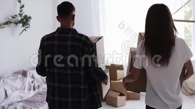 一对年轻夫妇搬进了一个新家。 一对夫妇正拿着箱子，然后放在地板上。 很漂亮的一对